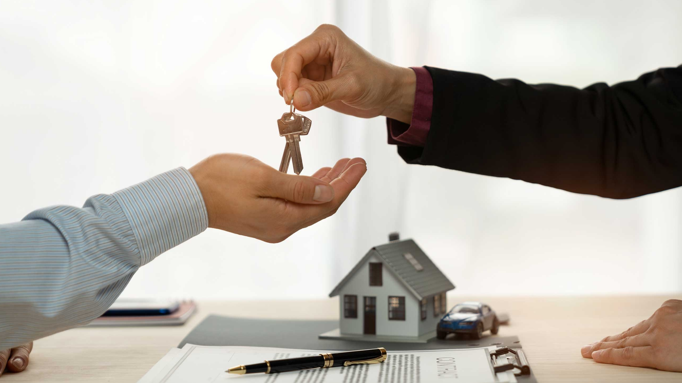 Handing over house keys above a model home, symbolising property investment opportunities and rising Australian suburbs despite high interest rates in 2026.