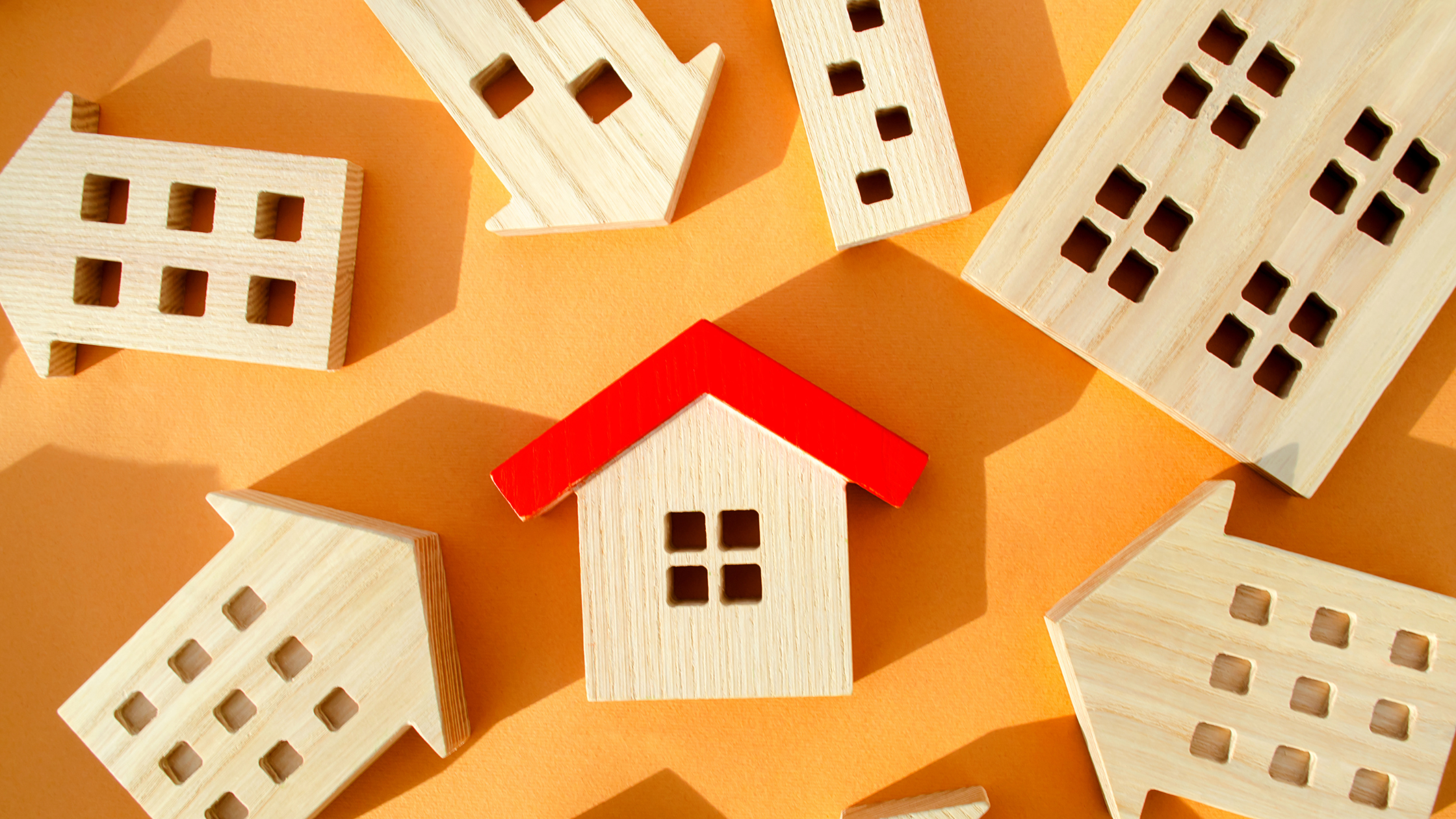 Red house model surrounded by smaller homes, representing outperforming and underperforming segments in Australia’s two-speed property market in 2026.