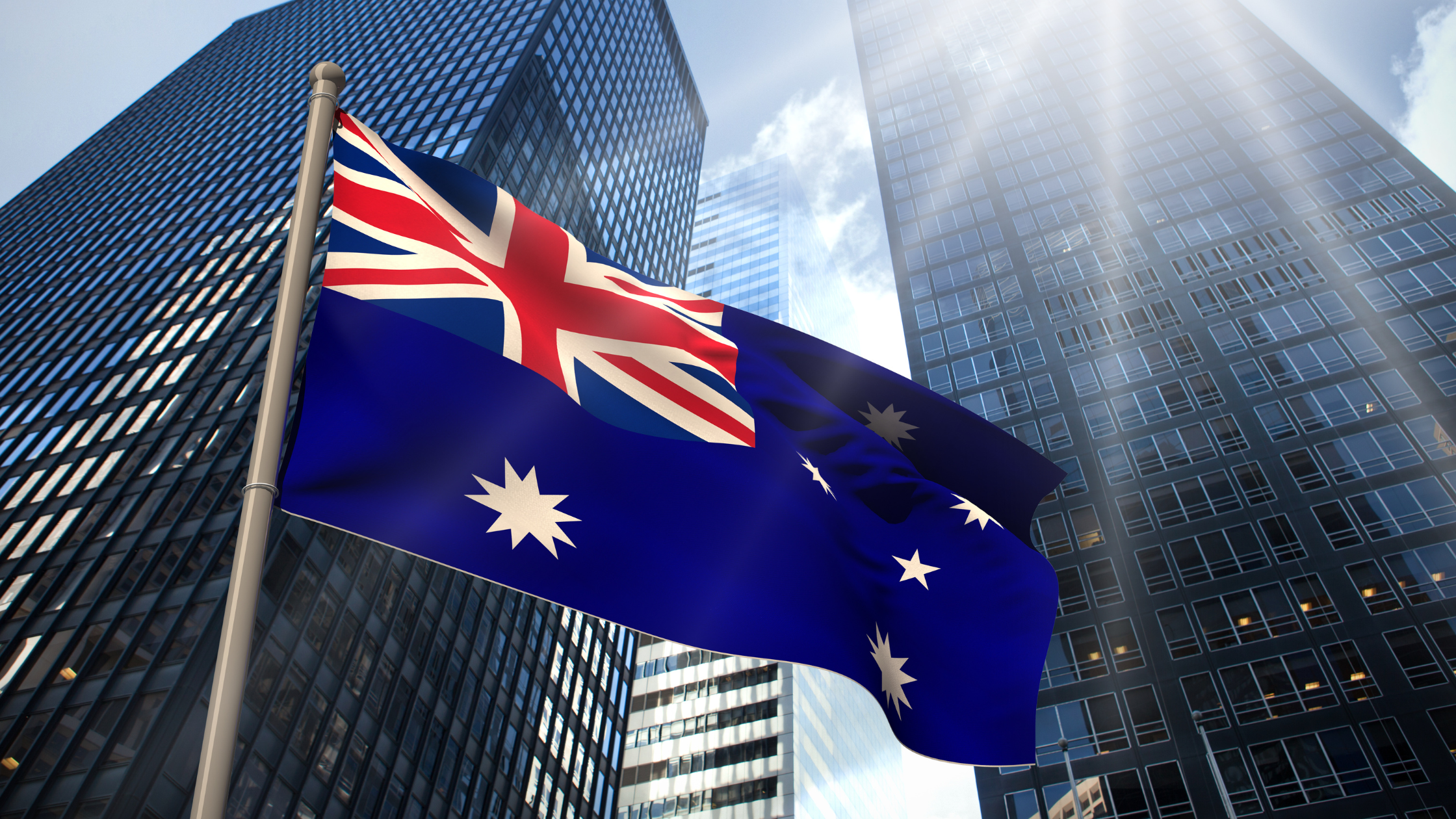 Australian flag in front of modern city buildings representing the Australian property market and real estate investment trends in 2026.