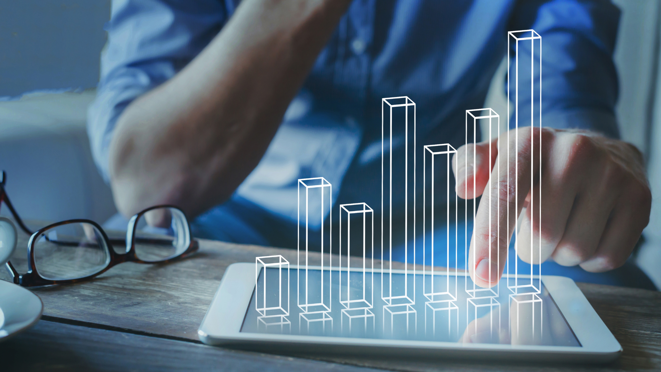 Person using a tablet displaying a digital bar chart with rising data columns, representing property market analysis, housing demand trends, population growth, and real estate investment insights in Australia.