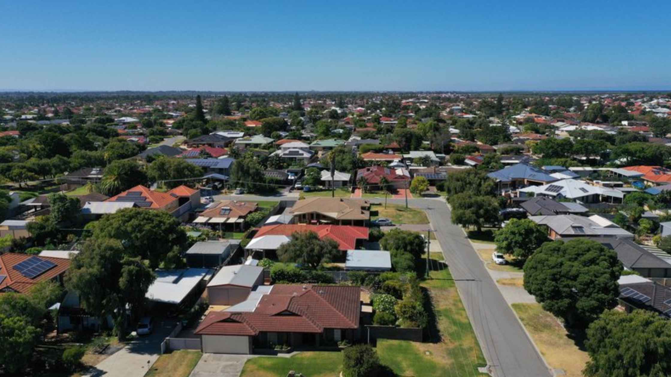 Aerial view of a residential suburb in Australia showing houses, streets and surrounding greenery.
