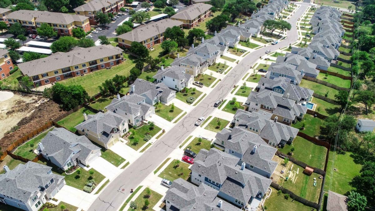 Aerial view of a residential neighbourhood showing detached homes, townhouses, streets, green spaces and ongoing housing development.