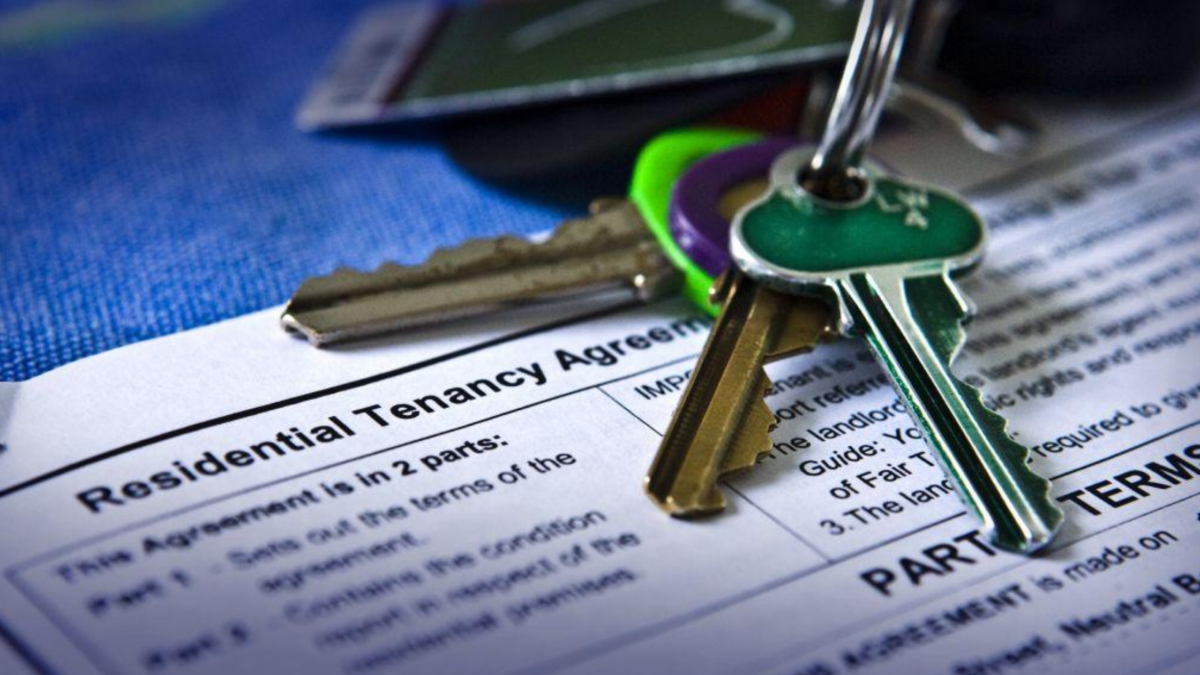 Keys resting on a residential tenancy agreement, representing a rental property purchase and existing tenant lease.